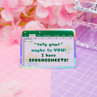 "Cozy game! Maybe to YOU! I have SPREADSHEETS!" holographic vinyl sticker